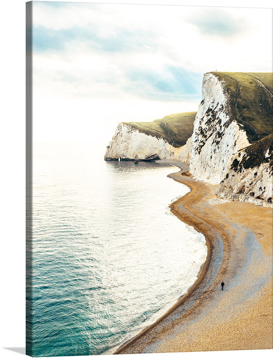 “Walking on Winding Sands” invites you to the edge of a world where land and sea embrace in timeless harmony. These majestic cliffs, like ancient guardians, stand tall against the horizon. Their white faces, etched by eons of wind and waves, exude a quiet strength. Below, a narrow beach curves gently, inviting solitary footsteps. A lone figure walks, a silhouette against the vastness, lost in contemplation.