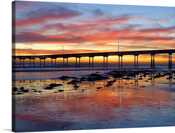 Immerse yourself in the serene beauty of a coastal sunset with this exquisite print. The artwork captures a tranquil scene where the golden hues of the setting sun paint a masterpiece across the sky, reflecting its warm tones onto the gentle waves below. A pier stands as a silent witness to nature’s spectacle, offering viewers a sense of stability amidst the ever-changing tides. 