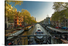  Capture the enchanting allure of Amsterdam with this captivating print. The image transports you to the heart of the Netherlands, where the iconic canals weave through the city like veins of life.