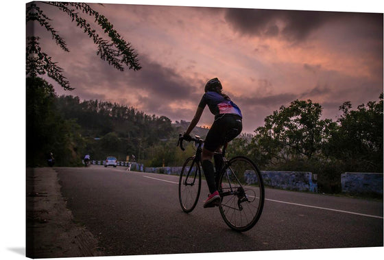 This exquisite print captures the serene beauty of Ooty, with a male cyclist pedaling along a picturesque treed road. The artwork is rich in detail and emotion, encapsulating the tranquil yet invigorating atmosphere of the region. The stunning sunset paints the sky with warm hues of orange and purple, creating a mesmerizing backdrop for the cyclist’s journey.