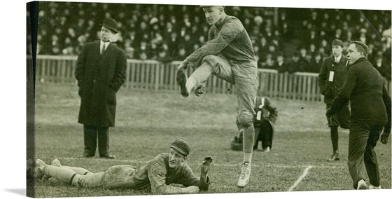 This captivating print captures a riveting moment from an early 20th-century football match. The black and white image is alive with action, featuring players in dynamic movement, their intensity indicative of the high stakes of the game. Spectators, dressed in period attire, add to the historical ambiance, their rapt attention underscoring the excitement of the event.