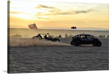  “Sand Dune” is a breathtaking print that captures the essence of an off-road adventure against the backdrop of a serene sunset. The image features two dune buggies racing across the pristine sands, their flags billowing gracefully in the wind, embodying a spirit of unbridled joy and liberty. 