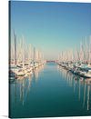 This artwork, titled “Serene Marina,” captures the tranquil beauty of a marina filled with elegant sailboats. The calm waters reflect the masts of the boats, creating a symmetrical visual effect that is both peaceful and captivating. The clear blue sky suggests perfect weather conditions, adding to the overall serenity of the scene. This print is more than just a piece of decor; it’s a window into a world of tranquility and luxury.