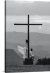 “Man and Woman with Cross” is a captivating piece of art that encapsulates the serene and profound connection between humanity and spirituality. This exquisite black and white print captures two figures in contemplative postures beside a towering cross, set against the backdrop of a tranquil landscape. The ethereal quality of the misty mountains, coupled with the gentle rise of the moon, evokes a sense of peace, reflection, and transcendence.