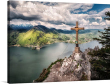  Immerse yourself in the serene beauty of this exquisite print. The artwork captures a moment of stillness atop a rugged mountain peak. A rustic wooden cross, symbolizing faith and endurance, stands resilient against the backdrop of a breathtaking landscape. The tranquil waters of a nestled lake reflect the lush greenery of the surrounding hills, while majestic mountains loom in the distance under a sky painted with soft, billowing clouds.