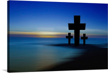  This photo-realistic image of three crosses on a beach at sunset is a peaceful and beautiful representation of the Christian faith. The largest cross is in the center, with two smaller crosses on either side, and the background is a stunning blue gradient with the horizon line visible in the distance. 