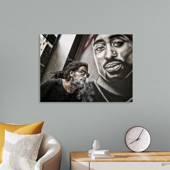 "Man With Dreadlocks and Sunglasses Poses Near Tupac Shakur Portrait"