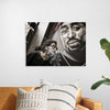"Man With Dreadlocks and Sunglasses Poses Near Tupac Shakur Portrait"