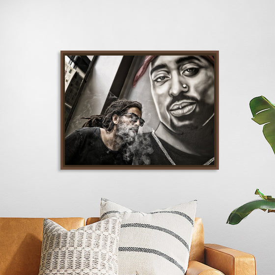 "Man With Dreadlocks and Sunglasses Poses Near Tupac Shakur Portrait"