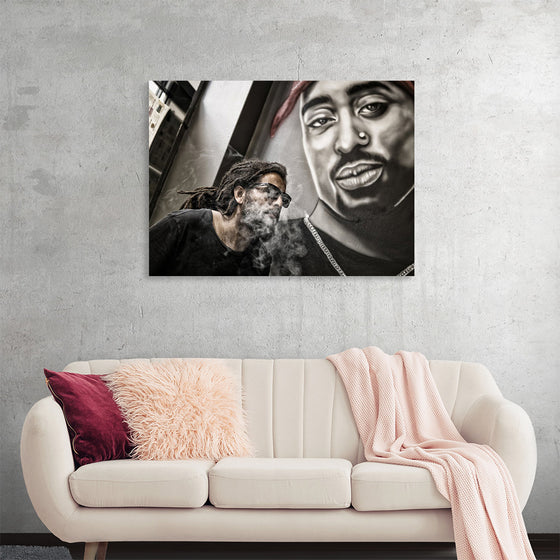 "Man With Dreadlocks and Sunglasses Poses Near Tupac Shakur Portrait"