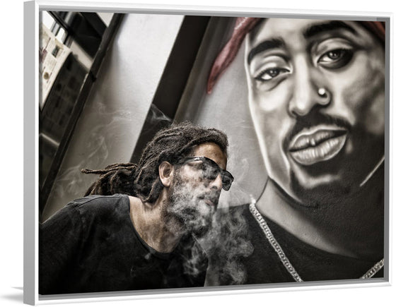 "Man With Dreadlocks and Sunglasses Poses Near Tupac Shakur Portrait"