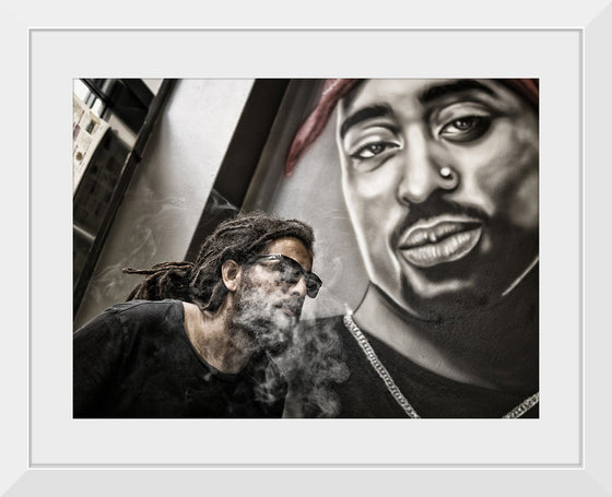 "Man With Dreadlocks and Sunglasses Poses Near Tupac Shakur Portrait"