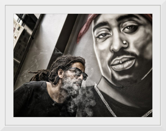 "Man With Dreadlocks and Sunglasses Poses Near Tupac Shakur Portrait"