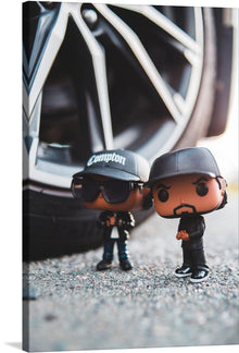  This captivating print, titled “Icons of the Era”, brings to life two iconic figures immortalized as stylized miniatures. Set against the backdrop of an intricate alloy wheel, these figures exude an aura of coolness and nostalgia. One figure, donning sunglasses and a cap marked “Compton,” evokes the legendary West Coast hip-hop scene. The other, dressed in black, mirrors the intensity and passion that defined an era.