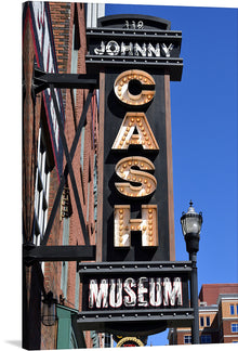  This artwork is a stunning print of the Johnny Cash Museum sign. The sign features a tall vertical design with “119 JOHNNY” in white letters against a black background at the top. Below that, “CASH” is spelled out in large capital letters adorned with illuminated marquee bulbs. At the bottom, “MUSEUM” is written in white capital letters on another black rectangular background. 