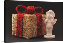  This beautiful print of a gift and an angel figurine is perfect for the holiday season. The gift is wrapped in gold and red glitter, and the angel is a lovely white porcelain. The image showcases a gift wrapped in gold and red glitter with a red bow on top, and a white porcelain angel figurine with wings and a halo. 