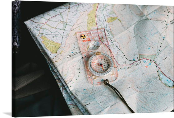 Embark on a journey of discovery with this exquisite print capturing the essence of adventure. The artwork features a detailed topographical map, intricately marked with contour lines, paths, and water bodies. A compass, the quintessential tool for navigation, lies gracefully atop the map, its metallic sheen contrasting the paper’s texture. 