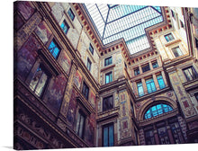  This print is a beautiful photograph of the interior of a grand Italian courtyard. The intricate details and stunning architecture make this a perfect piece for any art lover. The courtyard is surrounded by ornate walls and arches with intricate details. The walls are decorated with frescoes and sculptures. The courtyard has a glass roof that allows natural light to flood in. The image is taken from a low angle, looking up at the walls and roof. 