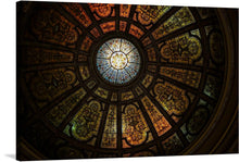  This print captures the mesmerizing beauty of a stained glass dome ceiling. The dome, composed of numerous small panels of stained glass in various colors and patterns, radiates with a vibrant glow. At the heart of the dome is a large circular panel, adorned with a captivating blue and yellow design. 