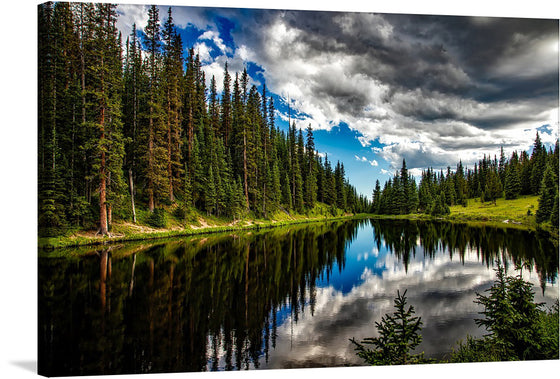 This exquisite landscape print invites you into a world of serene beauty. It captures a breathtaking view of a tranquil forest lake, surrounded by towering pine trees. The lush greenery is perfectly mirrored in the calm waters below, creating a mesmerizing mirror-like effect. The dramatic interplay between light and shadow under a sky painted with soft, billowing clouds adds depth to the scene.