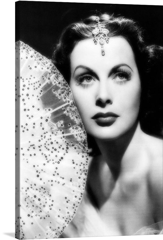 “Hedy Lamarr” is a captivating print that encapsulates the essence of one of Hollywood’s most iconic figures. The artwork, rendered in black and white, exudes a vintage charm that is beautifully contrasted by contemporary artistry. The subject, adorned with intricate embellishments and poised elegance, is captured with exquisite precision.