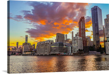  “New York City” is a captivating print that encapsulates the city’s dynamic spirit. The artwork features a breathtaking view of New York City’s skyline during sunset, with a myriad of buildings with varying architectures and heights prominently displayed. The sky is painted with vibrant hues of orange, yellow, and purple as the sun sets, and reflections from the buildings shimmer on the calm waters below. 