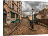 “Paris” is a captivating artwork that transports you to a serene street in the heart of the city. The print features a picturesque scene from a quiet street in Paris, with a cobblestone pathway leading the viewer’s eye through the image. On the left, there’s an old building with signage reading “AU LAPIN AGILE,” indicating it might be a business or café. 