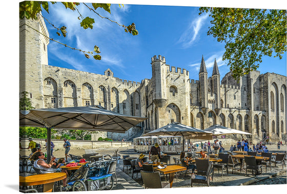 Immerse yourself in the grandeur of history with a print of “The Pope’s Palace In Avignon”. Every detail, from the towering stone architecture to the serene outdoor café scene, is captured with exquisite clarity. The artwork transports you to a sunny afternoon in Avignon, where the majestic palace stands as a testament to time, echoing stories of power and faith. 