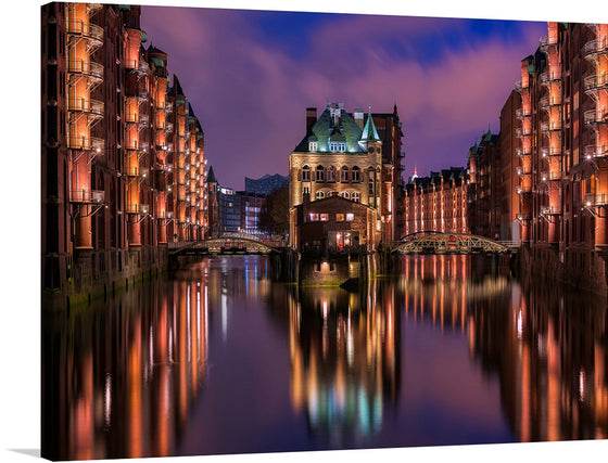 Immerse yourself in the enchanting allure of this exquisite artwork capturing a serene evening at the iconic Hamburg Speicherstadt. This print brings to life the mesmerizing reflection of illuminated windows and bridges on the tranquil waters, under a sky painted with hues of twilight. 