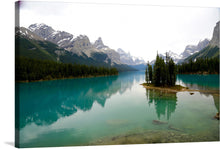  “Lake Panorama” by Jean Beaufort is a captivating print that encapsulates the tranquil beauty of nature. The image features a pristine, turquoise lake, nestled amidst towering, snow-capped mountains. The lake houses a small, forested island at its heart, serving as a serene focal point. The calm waters mirror the majestic peaks and lush greenery, creating a harmonious reflection that adds depth to the scene. 