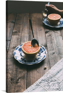  The photo captures the freshness of the fruit and the rustic charm of the wooden table. The vibrant pink color of the grapefruit contrasts beautifully with the blue and white plate.