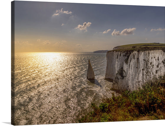 Immerse yourself in the serene beauty of “Old Harry Rocks, Dorset, England.” This exquisite print captures the iconic white chalk formations standing majestically against the backdrop of a golden sunset. The tranquil waters of the English Channel glisten, reflecting the warm hues of the sky, offering a scene of pure tranquility and natural splendor. Every detail, from the lush greenery crowning the cliffs to the gentle waves lapping at their base, is rendered with stunning clarity. 