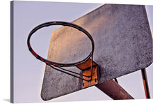  Capture the essence of the game with this striking print featuring an up-close view of a weathered basketball hoop against a soft, muted sky. The rich textures and subtle hues of rust and wear tell a story of countless games, victories, and defeats. Every mark and imperfection adds character, making it not just a piece of art but a slice of history.