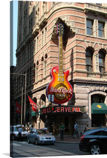  This stunning print titled “Hard Rock Cafe Philadelphia” by Italo2712 is a vibrant and detailed representation of the iconic establishment. The artwork features an exterior view of the cafe, located at the corner of an ornate stone building featuring detailed carvings and decorations. A large guitar-shaped signboard with “Hard Rock Cafe” written on it dominates the scene.