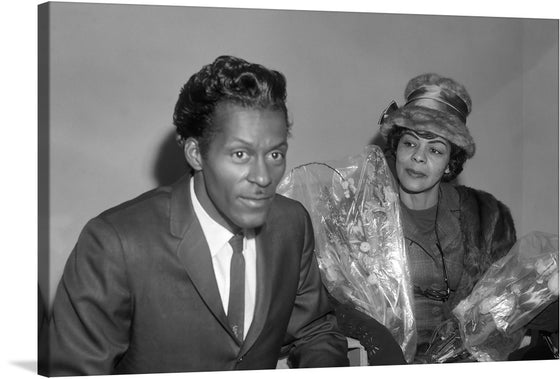 “Chuck Berry en Lucy Ann (1965)” by Joop van Bilsen is a striking black and white photograph that captures the essence of the era. The image features two blurred figures, one in a suit and the other in a hat and veil, with a bouquet of flowers. This print would make a great addition to any collection of vintage photography or mid-century art".