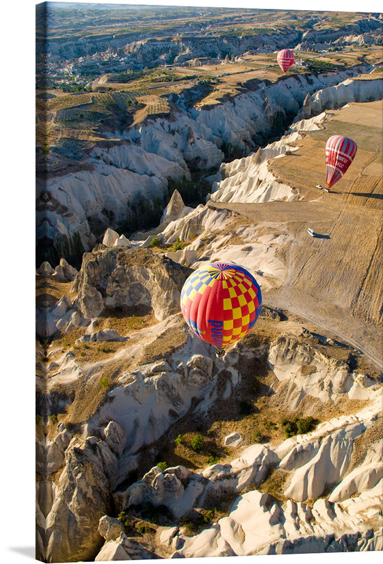 Elevate your space with this mesmerizing print capturing the serene and majestic dance of hot air balloons over the rugged terrains of Cappadocia. Each balloon, painted with vibrant hues, floats gracefully, offering a stark yet harmonious contrast to the earth-toned landscapes below.