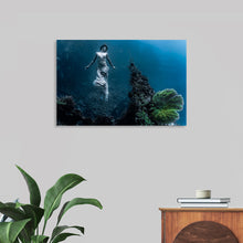  “Underwater Animals – Underwater Models: The Daughter of Poseidon 12” by Victor Hawk invites you to plunge into the mystical depths of the ocean. This exquisite print captures an ethereal scene beneath the waves, where light dances through the water to illuminate a figure surrounded by the serene beauty of underwater flora. 