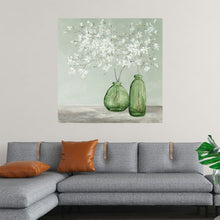  “Spring Delight Green” by Julia Purinton: Immerse yourself in the serene beauty of this exquisite print. Capturing the delicate dance of white blossoms, springing to life from within two vintage green glass bottles, it evokes a sense of renewal and growth. The soft, muted green backdrop sets the stage for nature’s elegance. 