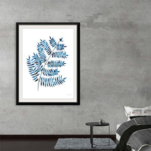  “Woodland Fern” by Mercedes Lopez Charro invites you into a tranquil forest realm. This captivating print celebrates the delicate beauty of fern leaves, meticulously painted in shades of blue against a pristine white backdrop. Each leaf dances with light and shadow, evoking a sense of calm and connection to nature. 